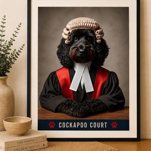 Op de afbeelding: Een ingelijste kunstdruk met een zwarte Cockapoo-hond gekleed in een traditionele pruik van een advocaat, een zwarte toga met rode accenten en een witte bef. De tekst COCKAPOO COURT staat onderaan gedrukt met twee rode pootafdruk-iconen.