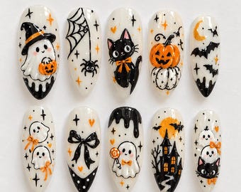 Może przedstawiać: Zestaw dziesięciu sztucznych paznokci w kształcie migdała z kremową bazą i wzorami halloweenowymi, takimi jak duchy, czarny kot, dynie, pajęczyna, nietoperze, nawiedzony dom i czarne kokardki z pomarańczowymi i czarnymi akcentami.