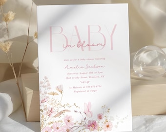 May include: A baby shower invitation with the text "BABY in bloom" in pink. The invitation features floral illustrations in pink and beige, with event details below. The invitation is on a white background.