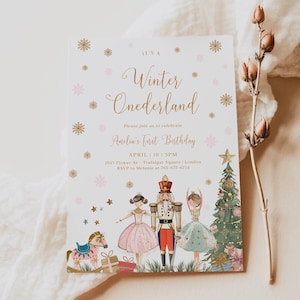 May include: A white invitation card with gold and pink snowflakes and stars. The text reads "It's a Winter Onederland. Please join us to celebrate Anelia's First Birthday. April 10 3PM. 1543 Flower Av. Trafalgar Square London. RSVP to Melanie at 765-675-6734". The card features a watercolor illustration of a nutcracker, two ballerinas, a rocking horse, and a Christmas tree.