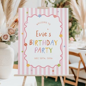May include: A rectangular birthday party welcome sign featuring a pink and white vertical striped background. The centre has a wavy-edged frame with the text Welcome to Evie's Birthday Party Dec 20th, 2026, decorated with small colourful flowers and stars.