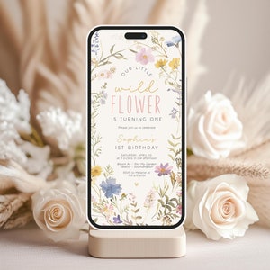 May include: A digital phone screen displaying a floral birthday invitation for a first birthday party. The invitation features a watercolor floral design with the text "Our Little Wild Flower is Turning One" and "Saphia's 1st Birthday".