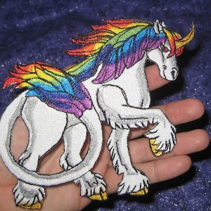 May include: A white, winged unicorn with a rainbow mane and tail. The unicorn has a gold horn and yellow hooves.