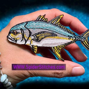 May include: Embroidered iron-on patch of a blue and yellow fish with black outlines. The fish is on a white background. The patch is approximately 3 inches long.  www.SpiderStitches.com