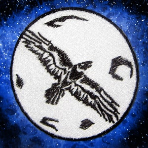 Pode incluir: Um remendo bordado branco com um corvo preto voando na frente de uma lua branca. A lua tem uma superfície texturizada e uma forma de lua crescente preta do lado direito.