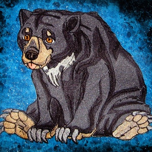 Può includere: Un cucciolo di orso nero con occhi marroni e una macchia bianca sul petto seduto su uno sfondo stellato blu e bianco.