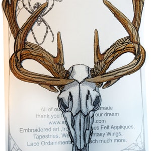 May include: Iron-on patch featuring a white embroidered deer skull with brown antlers. The patch is on a white background with text that reads "Iron on Patch" and "www.spiderstitches.com".