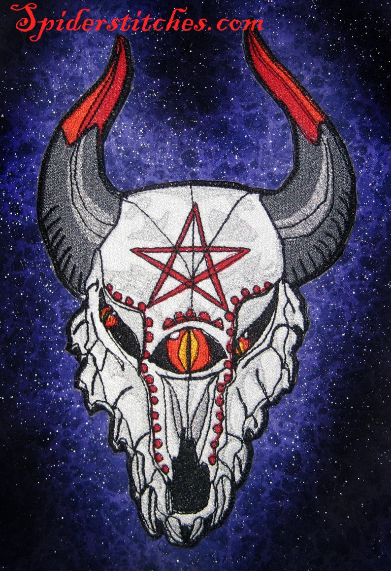 May include: Embroidered patch featuring a white skull with a red pentagram and a single red eye. The skull has horns and is set against a dark blue starry background. The text "spiderstitches.com" is visible at the top of the image.