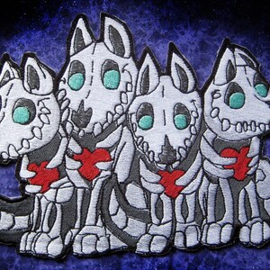 Puede incluir: Cuatro parches bordados de perros esqueleto sosteniendo corazones rojos. Los perros son blancos con contornos negros y tienen ojos turquesa.