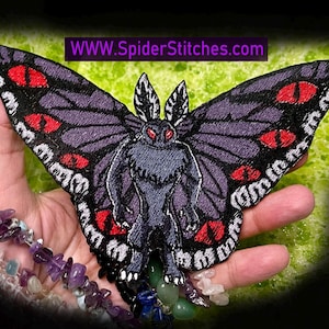 Op de afbeelding: Geborduurde patch met een mot-achtig wezen met een mensachtig lichaam, paarse vleugels met rode oogontwerpen en de tekst "WWW.SpiderStitches.com". De patch heeft een zwarte rand.