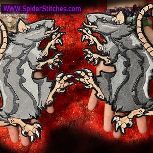 May include: Two gray embroidered rat patches with curled tails and sharp claws. The patches are on a red background.