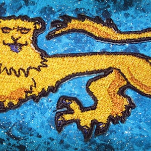 May include: A gold embroidered lion with a black outline on a blue sparkly background.