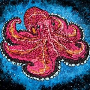 Puede incluir: Un pulpo bordado de color rosa y naranja con contorno negro sobre un fondo azul con purpurina blanca.