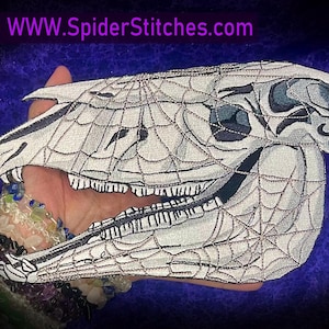 May include: Embroidered patch featuring a stylized horse skull design with a spiderweb overlay. The skull is white with black and gray details, and the spiderweb is intricately stitched. The text "WWW.SpiderStitches.com" is in purple.