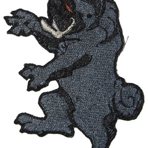 Puede incluir: Un parche bordado negro de un oso de pie con un diente blanco y un contorno negro.