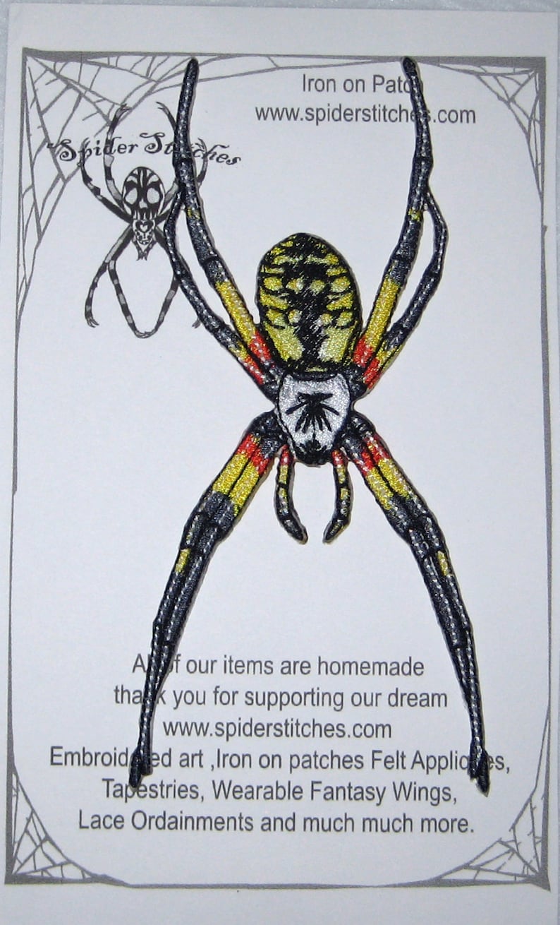May include: Iron-on patch of a yellow and black spider with red markings. The spider is on a white background with a black spider web border. The text "Iron on Patch" and "www.spiderstitches.com" is at the top of the image. The text "All of our items are homemade, thank you for supporting our dream www.spiderstitches.com Embroidered art, Iron on patches Felt Appliques, Tapestries, Wearable Fantasy Wings, Lace Ordainments and much much more." is at the bottom of the image.