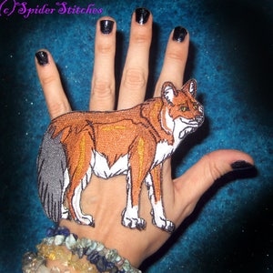 May include: Embroidered patch featuring a stylized fox in shades of brown, orange, white, and gray. The fox is depicted in a standing pose with detailed stitching. The patch is likely for clothing or accessories.