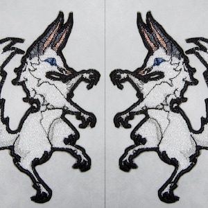 May include: Two white embroidered patches of a stylized fox with black outlines and blue eyes. The foxes are facing each other and are in a jumping pose.