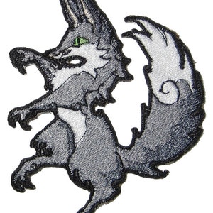 May include: A gray and white embroidered patch of a cartoon wolf with green eyes, standing on its hind legs with its tail curled up behind it.