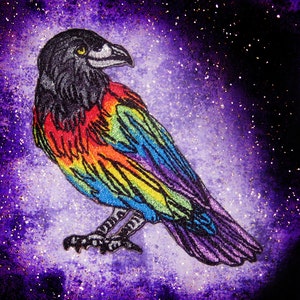 May include: A rainbow embroidered raven with black feathers against a purple and silver sparkly background.