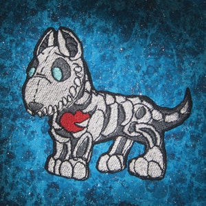 May include: A white embroidered patch of a skeleton dog with a red heart on its chest. The dog is standing on a blue background with white speckles.