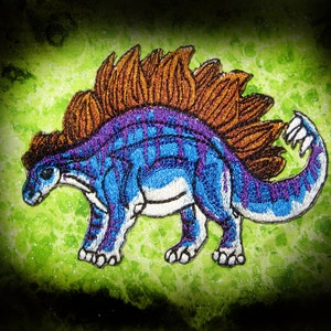 May include: Embroidered patch of a blue and purple dinosaur with a brown spiky back. The dinosaur is facing left and has a white underbelly.