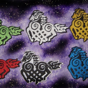 Puede incluir: Cinco diseños de caballos celtas de nudo bordados en diferentes colores: verde, blanco, dorado, rojo y azul. Los diseños están sobre un fondo morado con purpurina.