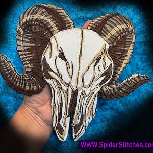 May include: Embroidered patch of a ram skull with large, detailed horns. The skull is white with brown details and the horns are brown with white stripes.