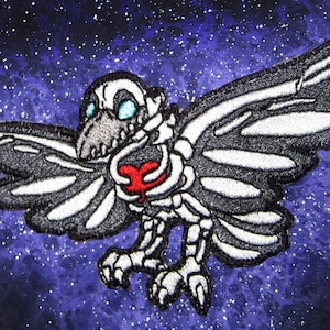 May include: A black and white embroidered patch of a skeletal raven holding a red heart in its chest. The raven is set against a dark blue background with white stars.