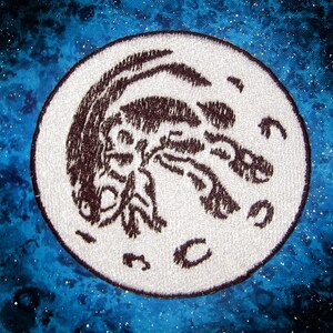 Peut inclure: Un écusson brodé blanc avec un motif de scorpion brun sur un fond bleu.