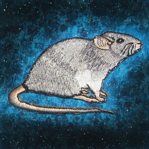 May include: A gray embroidered mouse with a long tail on a blue background with white glitter.