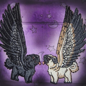 Puede incluir: Dos perros pug bordados con alas. Un pug es negro con alas negras y el otro es beige con alas marrones y blancas. Los pugs están sobre un fondo morado con estrellas.