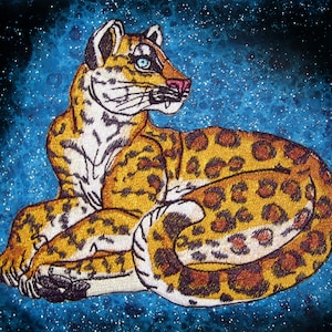 Puede incluir: Un parche bordado detallado de un leopardo con un patr&oacute;n de manchas marrones, doradas y blancas, acostado sobre un fondo azul brillante.