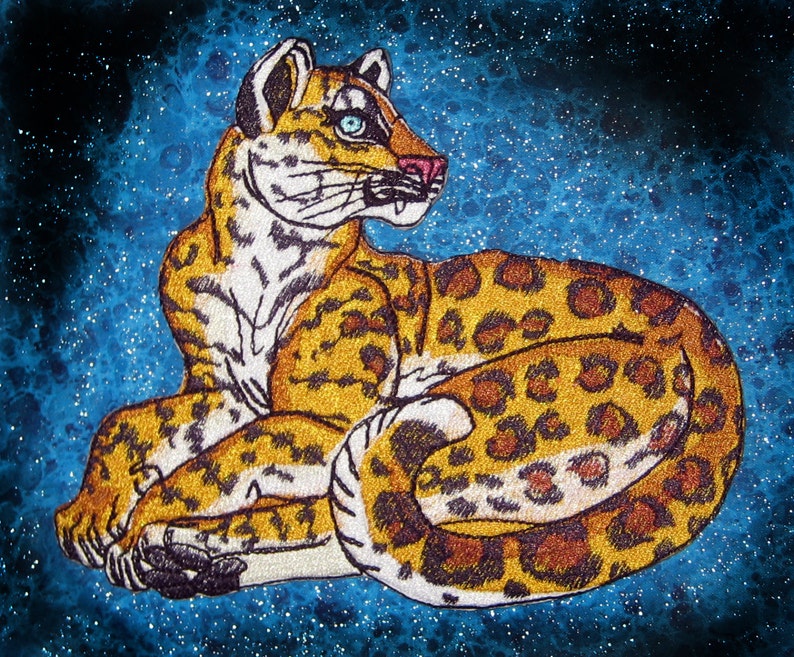 Puede incluir: Un parche bordado detallado de un leopardo con un patr&oacute;n de manchas marrones, doradas y blancas, acostado sobre un fondo azul brillante.