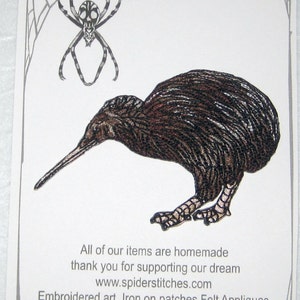Op de afbeelding: Een opstrijkbare patch met een gedetailleerde illustratie van een kiwi-vogel in bruin en zwart. De patch staat op een witte achtergrond met een spinnenwebrand en de tekst "Spider Stitches" en "www.spiderstitches.com".