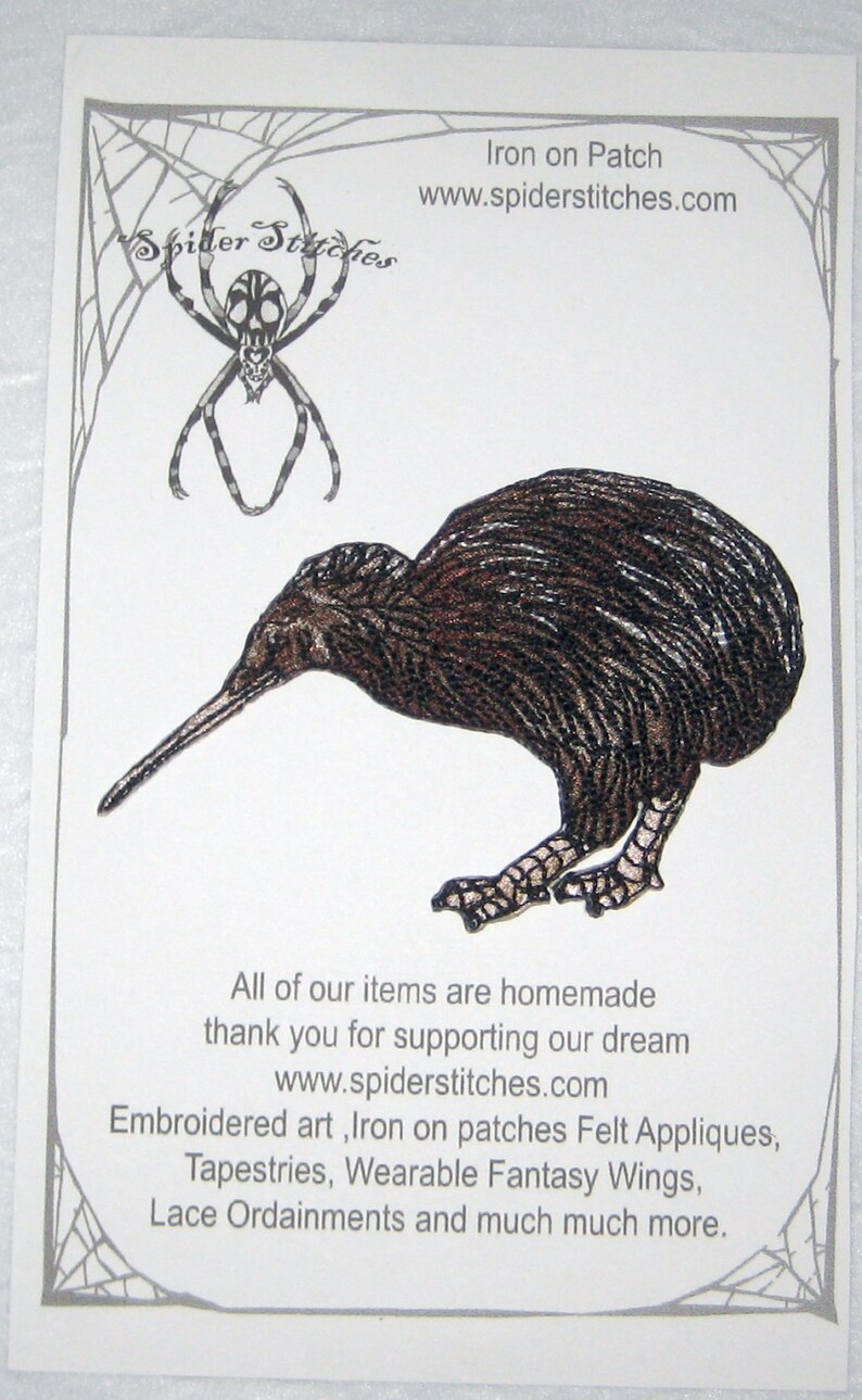 Op de afbeelding: Een opstrijkbare patch met een gedetailleerde illustratie van een kiwi-vogel in bruin en zwart. De patch staat op een witte achtergrond met een spinnenwebrand en de tekst "Spider Stitches" en "www.spiderstitches.com".