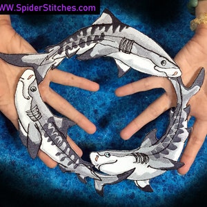 Puede incluir: Cuatro parches bordados para planchar de tiburones tigre en círculo, con fondo blanco y rayas grises y negras. Los parches están sobre un fondo azul con motas blancas.