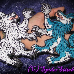May include: Two embroidered patches depicting a white and a blue dragon-like creature with a wolf head. The creatures are facing each other with their front paws raised. The white dragon has a curled tail and the blue dragon has a straight tail. The patches are on a purple background.