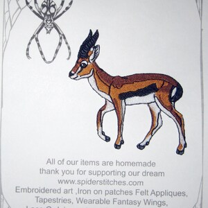 May include: Embroidered iron-on patch featuring a gazelle in shades of brown, black, and white. The patch is part of a collection of embroidered art, felt appliques, tapestries, and wearable fantasy wings. The text "Spider Stitchies" and website address are also visible.