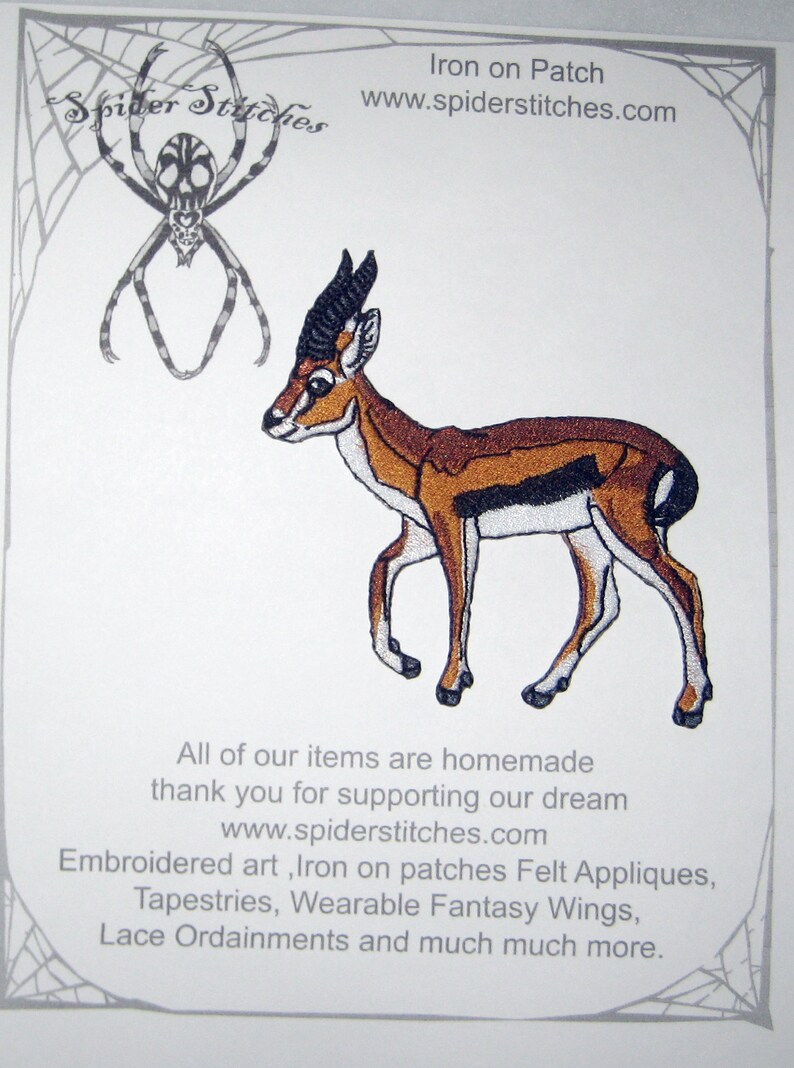 May include: Embroidered iron-on patch featuring a gazelle in shades of brown, black, and white. The patch is part of a collection of embroidered art, felt appliques, tapestries, and wearable fantasy wings. The text "Spider Stitchies" and website address are also visible.