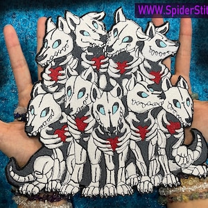 Puede incluir: Un parche bordado blanco de un grupo de perros esqueléticos que sostienen corazones rojos. El parche está sobre un fondo azul.