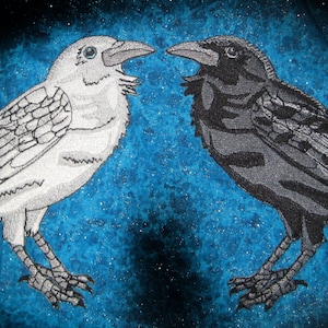 Könnte beinhalten: Zwei gestickte Raben, die sich auf einem blauen Hintergrund gegenüberstehen. Ein Rabe ist weiß und der andere ist schwarz.