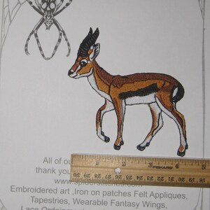 May include: Embroidered iron-on patch featuring a gazelle in shades of brown, black, and white. The patch is approximately 3 inches long. The patch is on a white background with a spider web design and the text "Spider Stitches".