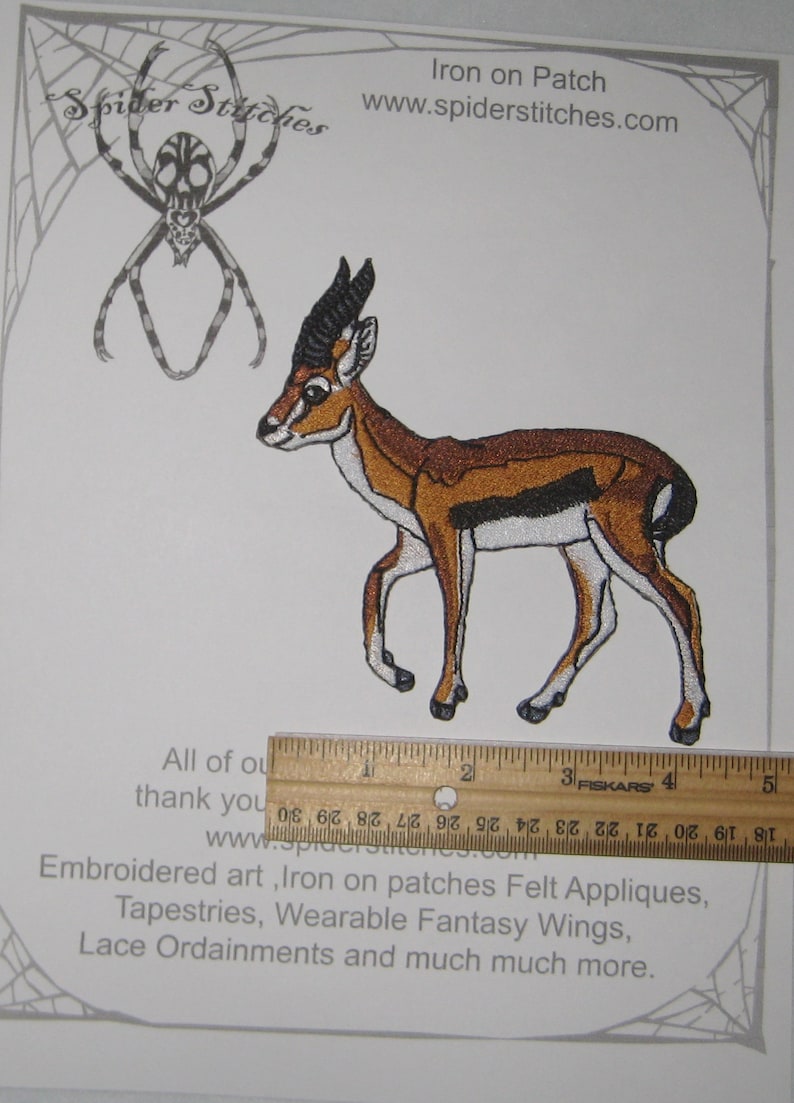 May include: Embroidered iron-on patch featuring a gazelle in shades of brown, black, and white. The patch is approximately 3 inches long. The patch is on a white background with a spider web design and the text "Spider Stitches".