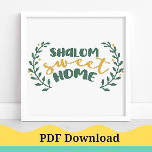 Peut inclure: Un cadre blanc avec un motif de point de croix vert et or qui dit "Shalom Sweet Home".