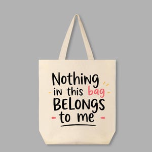 May include: A white canvas tote bag with the text "Nothing in this bag BELONGS to me" in black and pink lettering.