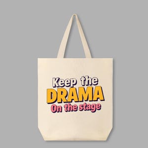 May include: A white canvas tote bag with the text "Keep the DRAMA On the stage" in yellow and pink lettering.