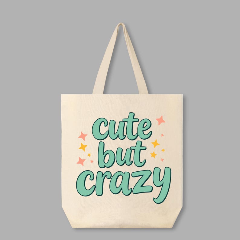 May include: A white canvas tote bag with the text "cute but crazy" in teal green lettering with pink and yellow stars.