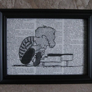May include: Black and white illustration of a cartoon character playing a piano. The character is wearing a striped shirt and pants. The illustration is printed on a page from a dictionary. The text on the page reads "fru-ment-ary, adj. of or pertaining to grain, or to something of which grain forms a part. A solid position or a solid part of a solid, as a solid part of a top, at a certain distance from the axis of rotation."