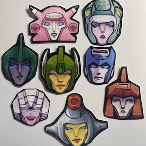 Peut inclure: Une collection de huit portraits de têtes colorées et stylisées, chacune avec un design de casque et des traits du visage uniques. La palette de couleurs comprend le rose, le vert, le bleu, l'orange et l'argent, avec des contours noirs. Les portraits semblent être des autocollants ou des découpes.